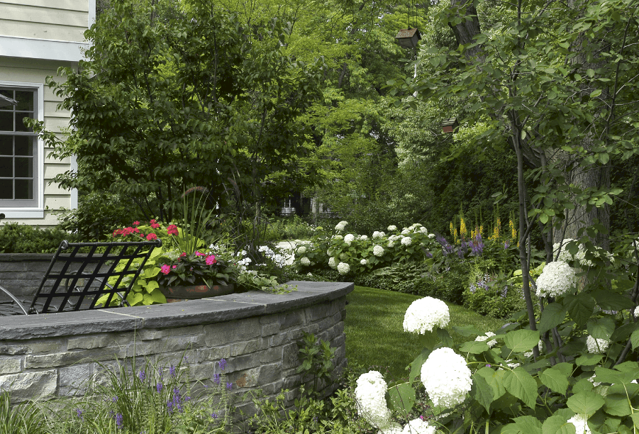 stacked stone seat wall capped with bluestone and surrounded by lush perennial beds